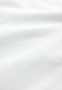 Textil alb cu o suprafață netedă, ușor texturată, care prezintă cute și pliuri subtile, indicând flexibilitate și moliciune.