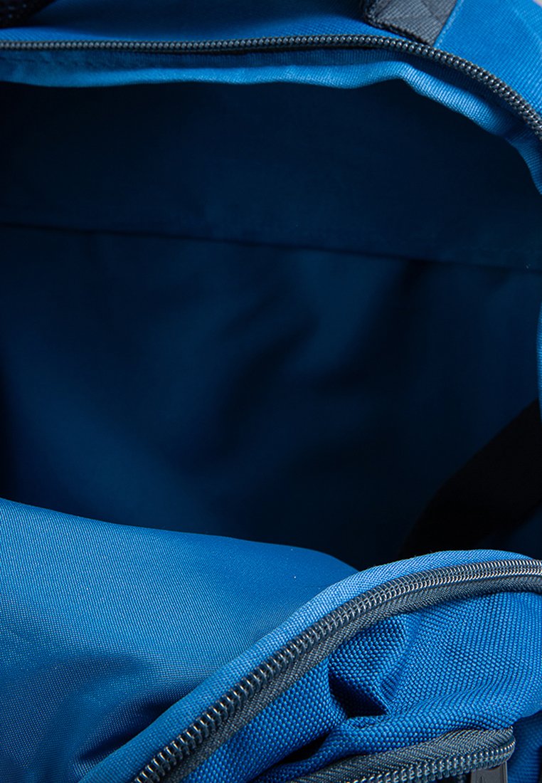 Mochila de tela azul con una cremallera abierta que muestra un compartimento principal vacío en el interior.