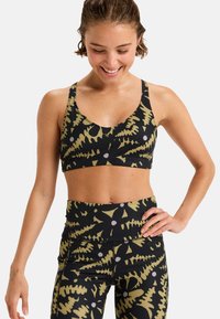Un reggiseno sportivo nero e leggings con un motivo foglioso verde e bianco. Realizzati in tessuto elasticizzato con una texture liscia e un design aderente.