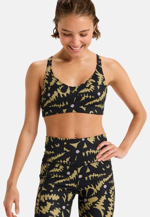 Sujetador deportivo negro y leggings con un patrón de hojas verdes y blancas. Fabricados con una tela elástica de textura suave y diseño ceñido.