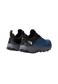 Zapatillas deportivas negras y azules con una parte superior texturizada, talón reforzado y una suela gris con un dibujo profundo para tracción.