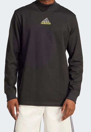 Schwarzer Langarm-Sweatshirt aus Baumwollmischung, mit hohem Kragen und einem gelben adidas-Logo, das auf der Brust zentriert ist. Glatte Textur.