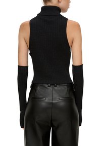 Schwarzes, geripptes, ärmelloses Turtleneck-Oberteil mit langen, eng anliegenden Ärmeln. Getragen mit eng anliegenden schwarzen Lederhosen, was eine schlanke Silhouette betont.
