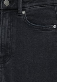 Jean en denim noir présentant un design classique à cinq poches, des coutures visibles et des accents en métal sur les poches.