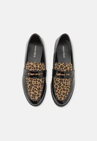 Mocassins noirs en vernis avec un panneau en tissu imprimé léopard sur le devant. Texture lisse avec une finition brillante, conception légère.