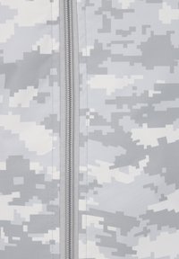 Gros plan d'une fermeture éclair fermée avec un motif camouflage numérique gris et blanc sur tissu.