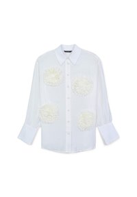 White long-sleeve button-up blouse with large white 3D floral appliques on front and wide cuffed sleeves.