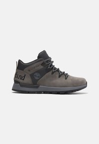 Botas de senderismo impermeables grises que presentan una combinación de cuero y material sintético, suela de goma gruesa y cordones negros con acentos de logo.
