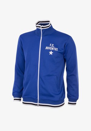 Blå zip-up jakke lavet af blødt stof, med høj krave, hvide striber på kraven og manchetterne, samt et hvidt logo med en stjerne.