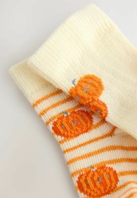 Textured yellow socks with orange pumpkin motifs and white stripes, featuring a soft knit material and decorative blue accents.
