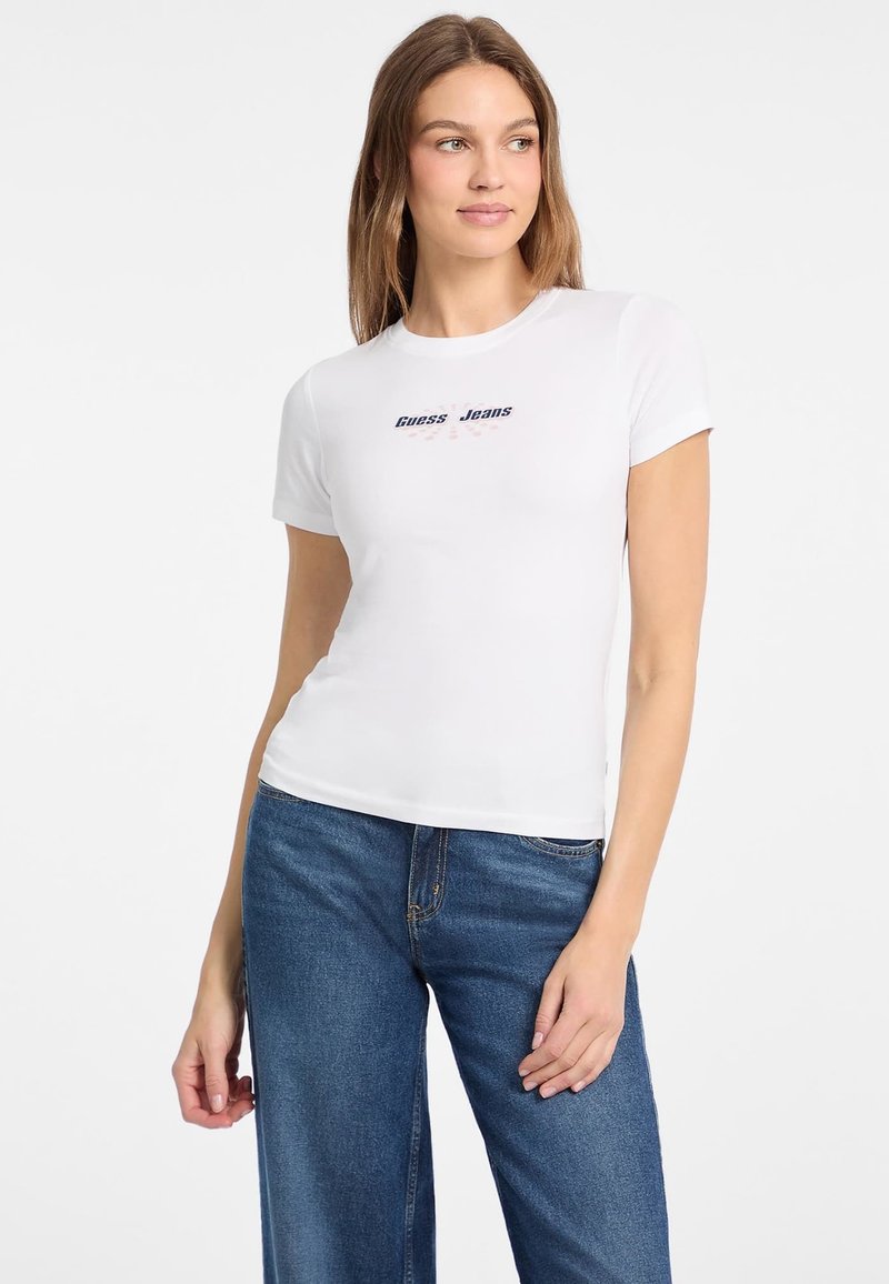 Biela bavlnená tričko s priliehavým strihom a krátkymi rukávmi, s logom "Guess Jeans" v modrej a červenej farbe umiestneným v strede na prednej strane.