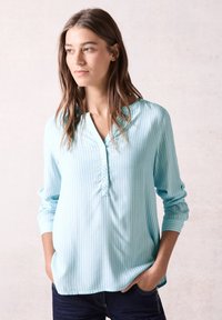 Blusa a righe blu chiaro con patta bottonata e scollatura arrotondata. Maniche lunghe con vestibilità comoda. Tessuto morbido.