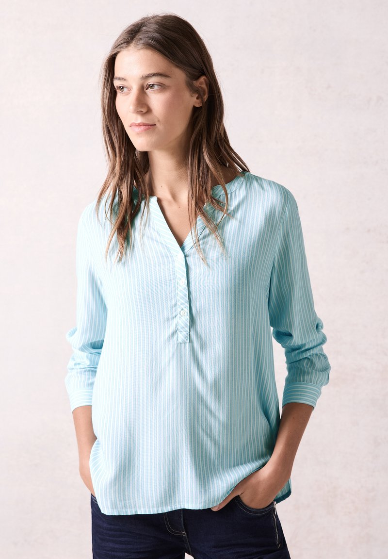 Blusa a righe blu chiaro con patta bottonata e scollatura arrotondata. Maniche lunghe con vestibilità comoda. Tessuto morbido.