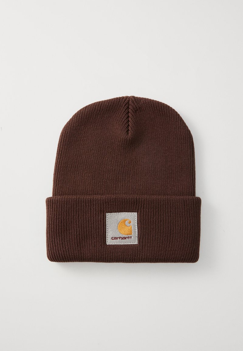 Gorro de punto marrón con dobladillo. Presenta un parche cuadrado con un logo amarillo y el nombre de la marca en costura gris. Tejido con textura y elástico.
