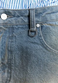 Denim jeans med en blå vask, der har en metalknaplukning, en flad front med en løkke og synlige stikninger på lommerne.