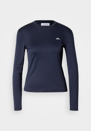 Langermet navyblå skjorte laget av glatt, elastisk stoff. Har rund hals og en liten hvit logo på øvre venstre bryst.