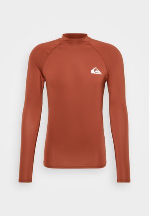 Long-sleeve rash guard in rust orange fabric with a fitted design. Features a high neck and a white logo on the left chest.