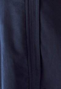 Tamsiai mėlynas audinys su lygiu pavir�šiumi, turintis išskirtinę vertikalią siūlę. Medžiaga atrodo tvirta ir lengva.