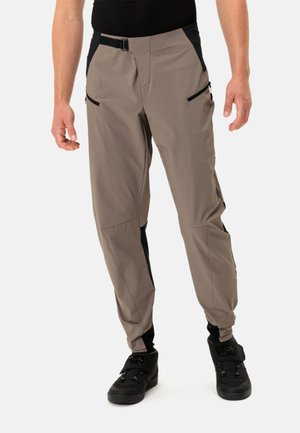 Lichte, beige outdoor broeken met zwarte zijpanelen, twee ritszakken aan de voorkant en een verstelbare tailleband. Soepele textuur, taps toelopende pasvorm.