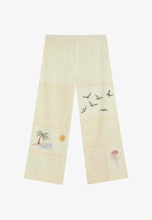 Pantalones anchos en color crema con bordados de palmera, sol, pájaros volando y medusas rosas en la parte inferior de las piernas.