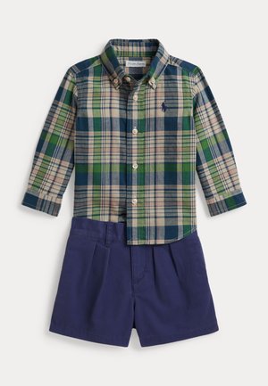 Chemise à manches longues boutonnée avec motif à carreaux vert, bleu et beige, associée à un short bleu marine.