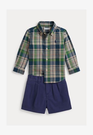 Langärmliges Hemd mit Knöpfen und grün-blau-beigem Karomuster, kombiniert mit marineblauen Shorts.