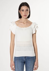 Witte gebreide top met korte gerimpelde mouwen, voorzien van een gegolfde halslijn en horizontale gaatjesdetails langs het lichaam.