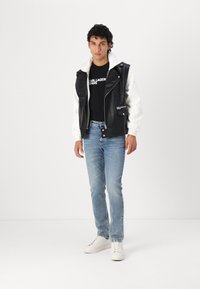Black and white leather jacket with a hood, worn over a black t-shirt, paired with light blue jeans and white sneakers. Simple design, minimal details.