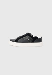 Zwarte sneaker met glanzend leren en suède panelen, witte zool en zwarte veters. Bevat een logo aan de zijkant en een contrasterend hieldetail.