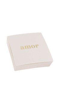 Krämfärgad fyrkantig smyckeslåda med guldtexten "amor" centrerad på locket, mot en vit bakgrund.