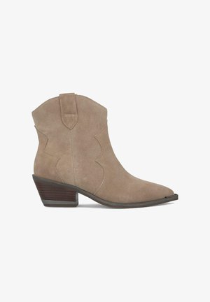 Stivali ankle in suede beige con punta appuntita, dettagli di cucitura curvi e tacco impilato. Presentano una linguetta per una facile infilatura.