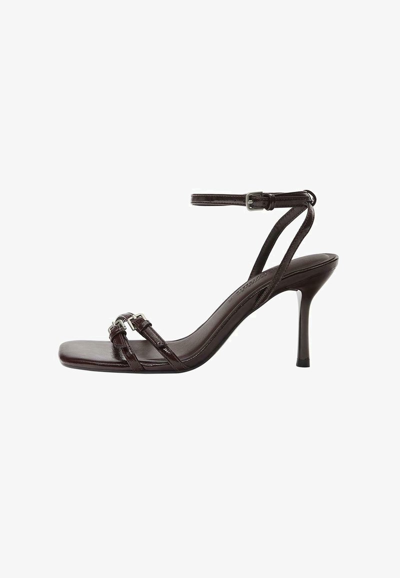 Tmavohnedá kožená sandála na vysokom podpätku s tenkým popruhom okolo členka a dvoma prednými popruhmi so striebornými prackami.