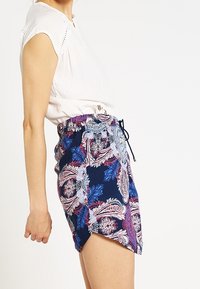 Shorts in stampa paisley blu navy con vita regolabile, caratterizzati da accenti floreali in viola e blu. Tessuto leggero, design con spacco laterale.