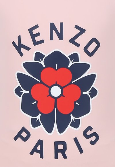 Un tissu en coton rose présente un graphique d'une fleur rouge et marine avec un centre blanc, entouré du texte "KENZO" et "PARIS" en gras noir.