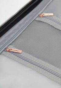 Szara saszetka podróżna o gładkiej fakturze, z kieszeniami z siateczki i różowo-złotymi zamkami błyskawicznymi. Na suwaku znajduje się nazwa marki "WITTCHEN".