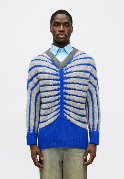 Μπλε και γκρι πλεκτό πουλόβερ με V λαιμόκοψη, διαθέτοντας ραβδωτά σχέδια και αντίθετες ρίγες, υφή και χαλαρή γραμμή.