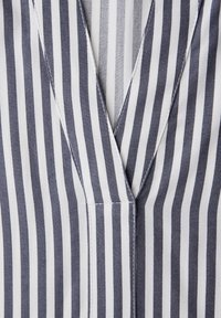 Tissu rayé verticalement bleu marine et blanc avec une couture en V superposée et des détails de couture visibles.