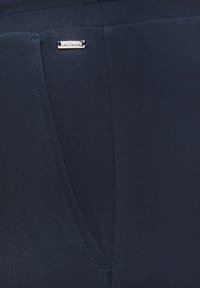 Navy blue leggings made of smooth stretchy fabric, featuring a small silver logo accent and a fitted design.