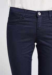Mörkblå denimjeans med slim fit, femficksdesign, stickade detaljer och en silverknappstängning vid midjan.
