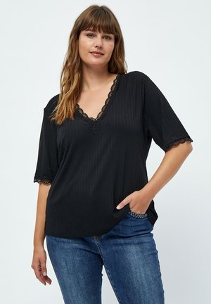 Top nero a coste con scollatura a V, rifiniture in pizzo alle maniche e all'orlo, e maniche corte, abbinato a jeans blu.