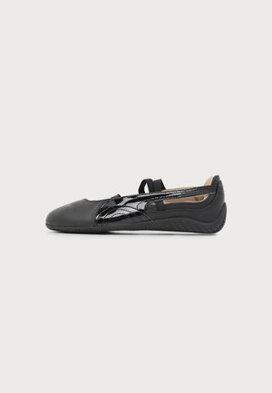 Ballerine plate en cuir noir avec des détails en cuir verni sur les côtés et des brides élastiques sur le dessus du pied, vue de l'extérieur sur fond blanc.