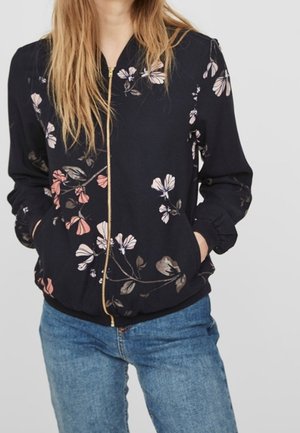 Mörkblommig zip-up bomberjacka med långa ärmar, ribbad mudd och fåll. Har rosa och beige blommönster på en svart bakgrund.