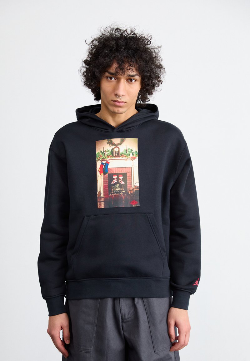 Sudadera negra con un gráfico frontal que representa una escena de chimenea. Presenta un bolsillo tipo canguro y puños acanalados. Confeccionada en tela suave.