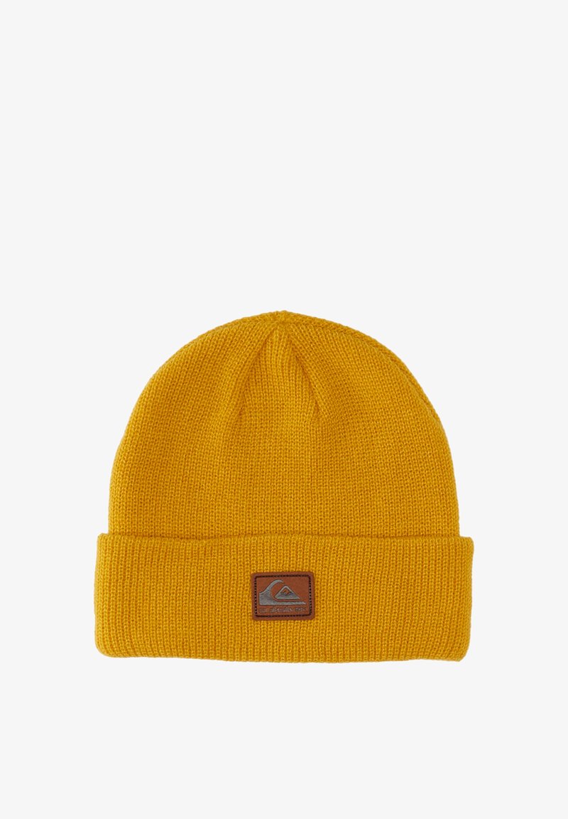 Dzianinowa żółta czapka z wywinięciem, z brązową łatką z logo. Gruba tekstura z prostym, bezszwowym wzornictwem.