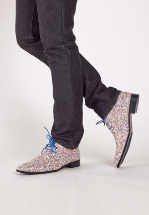 Patronen jurk schoenen in meerkleurige geweven textiel met blauwe veters, in contrast met donkere spijkerbroeken, met een ronde neus en platte hak.