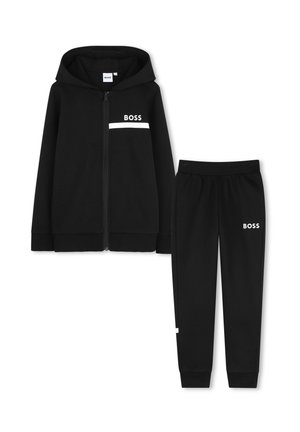 Sweat à capuche noir zippé et pantalon de jogging assorti avec le texte blanc "BOSS" et une bande sur la poitrine et la cuisse.