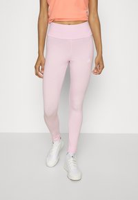 Leggings rosa chiaro realizzati in tessuto elasticizzato con una vita alta, con un piccolo logo bianco sulla coscia, abbinati a sneaker bianche.