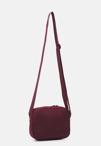 Bordeaux crossbody taske lavet af blødt stof, rektangulær form, med lynlåslukning og justerbar rem. Glat tekstur og minimalistisk design.