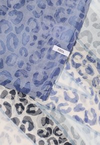Lightweight fabric with blue, black, and gray leopard print patterns and a white label with "CECIL" text sewn into the edge.