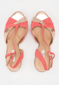 Różowe zamszowe sandały z złotą metaliczną osłoną na palce i paskami. Posiadają regulowany pasek na kostkę oraz gładkie wykończenie wewnętrzne.